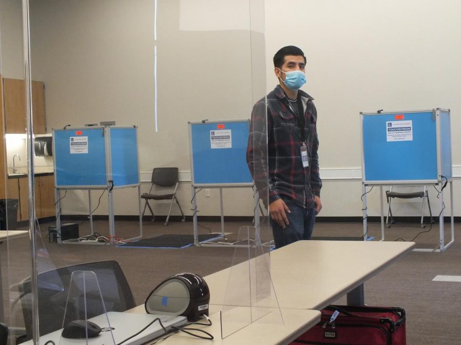 Jorge Perez, Sacramento County election assistant, stands in front of voting booths inside the ARC community room that he and a group of Sacramento county assistants set up for the college for early voting and Election Day. (Photo by Irvis Orozco)