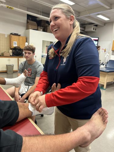 All in a day’s work: Michelle Whitehead, an athletic trainer with the American River College Kinesiology & Athletics department, wraps a football player’s ankle on Nov. 15. (Photo by Gina Gangursky)
