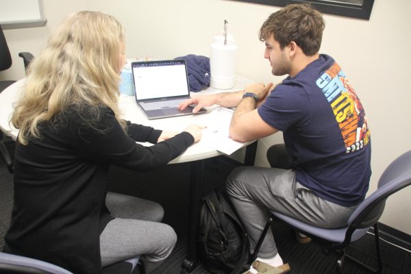 Leah Arambel, a Reading Across the Disciplines coordinator, helps ARC student Colin Denny, a business major with his economic studies in the RAD conference room on March 5, 2024. (Photo by Elisha Chandra)
