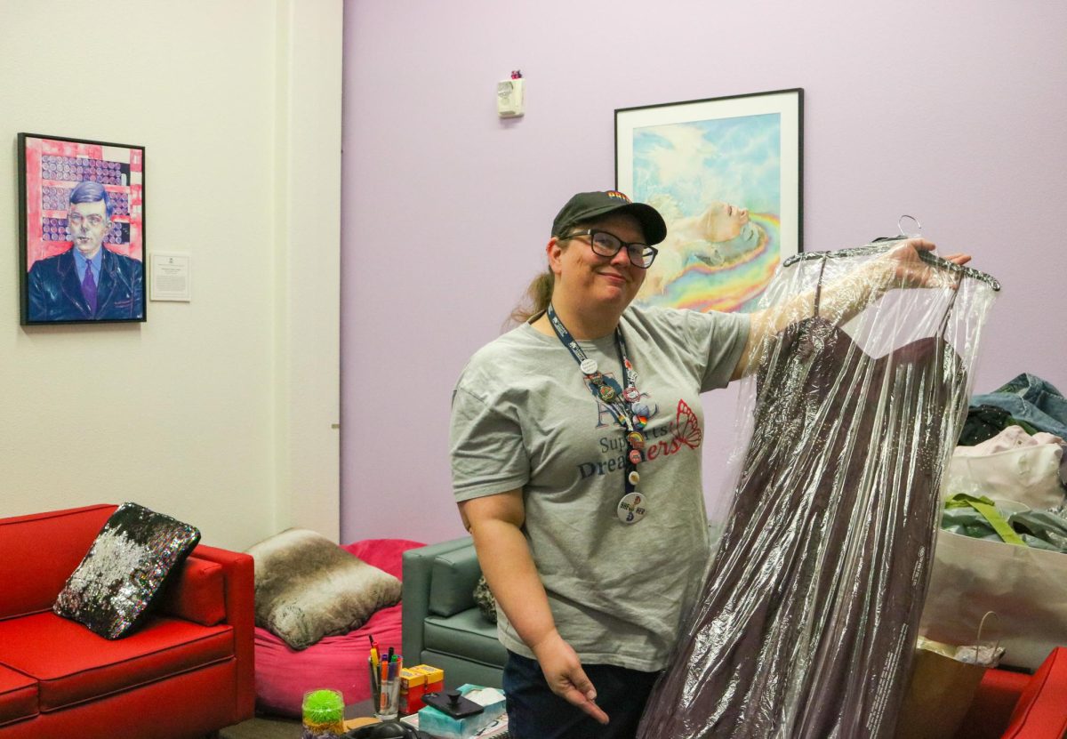 Liz Geisser, student support assistant for the Pride Center, shows off a prom dress on April 5, 2024 that was accumulated through the Pride Center’s clothing drive. (Photo by Shy Bell)