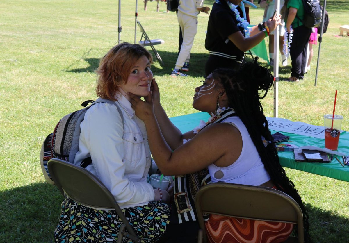 English and Theatre major Katie Stepp gets her face painted by General Education major Daianna Williams at the first annual Bucky Island Festival on the American River College main campus on May 2, in celebration of the end of the semester, finals, and for graduating students.

Snow cones, balloon animals, face paint, card tricks, and an inflatable surfrider peppered the lawn in front of the library, providing students with fun activities to help mitigate the stress of finals, or the transition of their next step in life.
